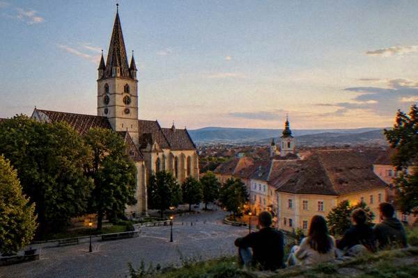 A hillside viewpoint looks over town rooftops at dusk.