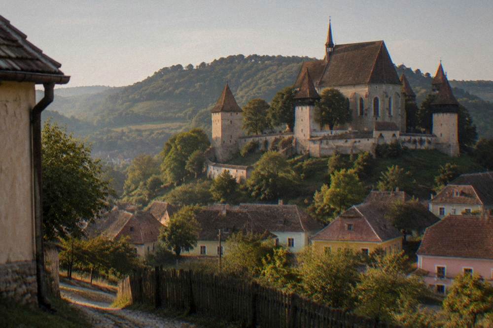 A white fortified church stands on a hill above a Saxon village.